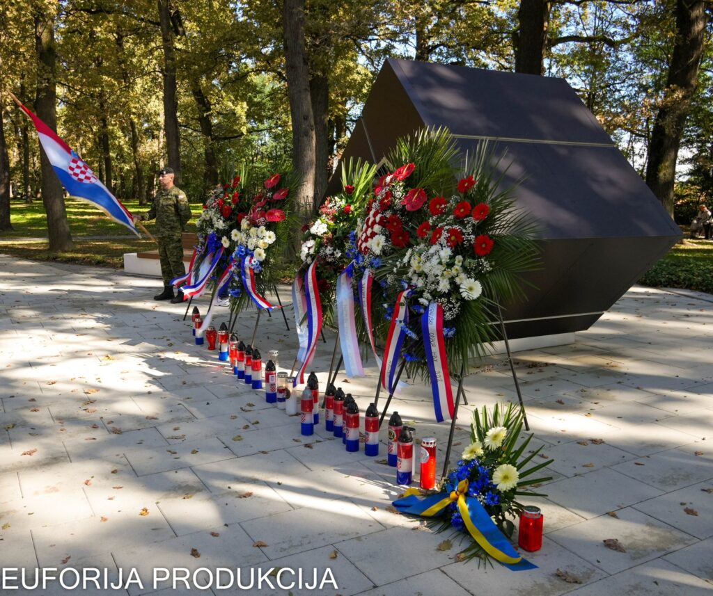 pomenik poginulim hrvatskim braniteljima u središnjem gradskom parku u Bjelovaru. Ispred spomenika položeni su vijenci i zapaljene svijeće, dok počasnu stražu drži hrvatski vojnik s državnom zastavom.