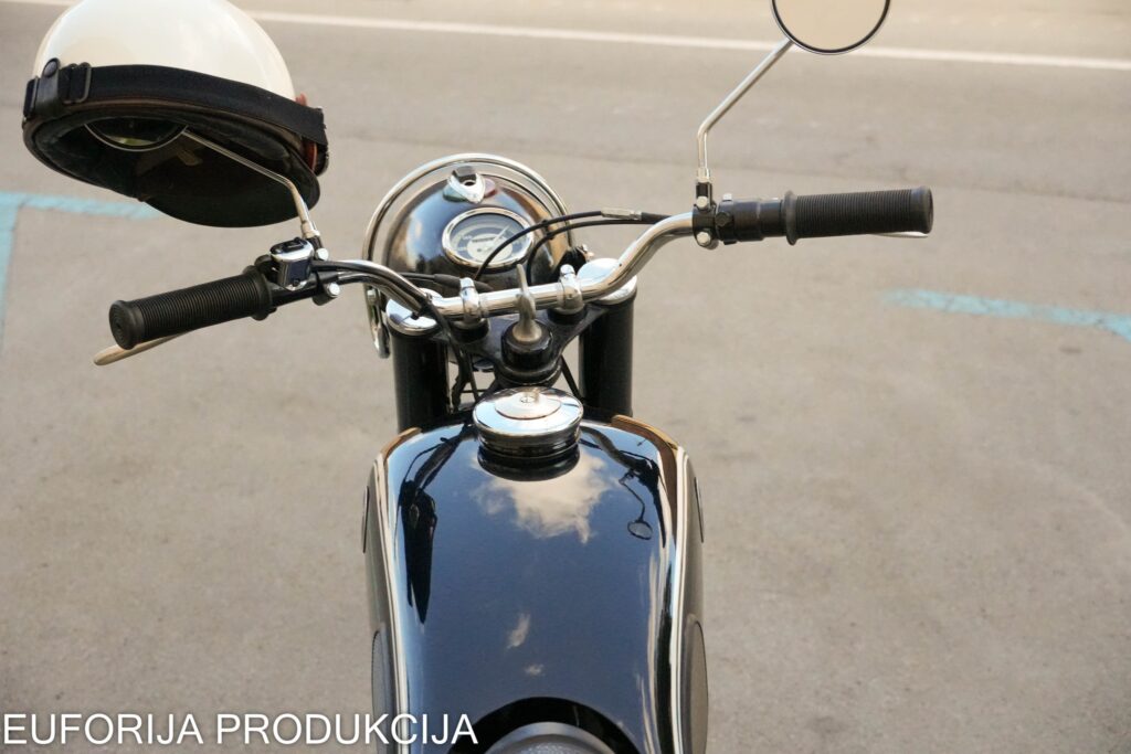 Vintage motor spreman za Moto Alku u Bjelovaru - pogled na upravljač, sjajni rezervoar i bijelu kacigu.